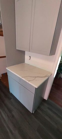 A small kitchen cabinet with a light gray countertop, pale blue cabinets, and dark gray flooring.