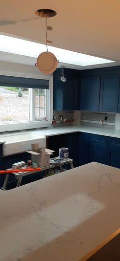 Kitchen under renovation with navy blue cabinets, white countertops, and a skylight.