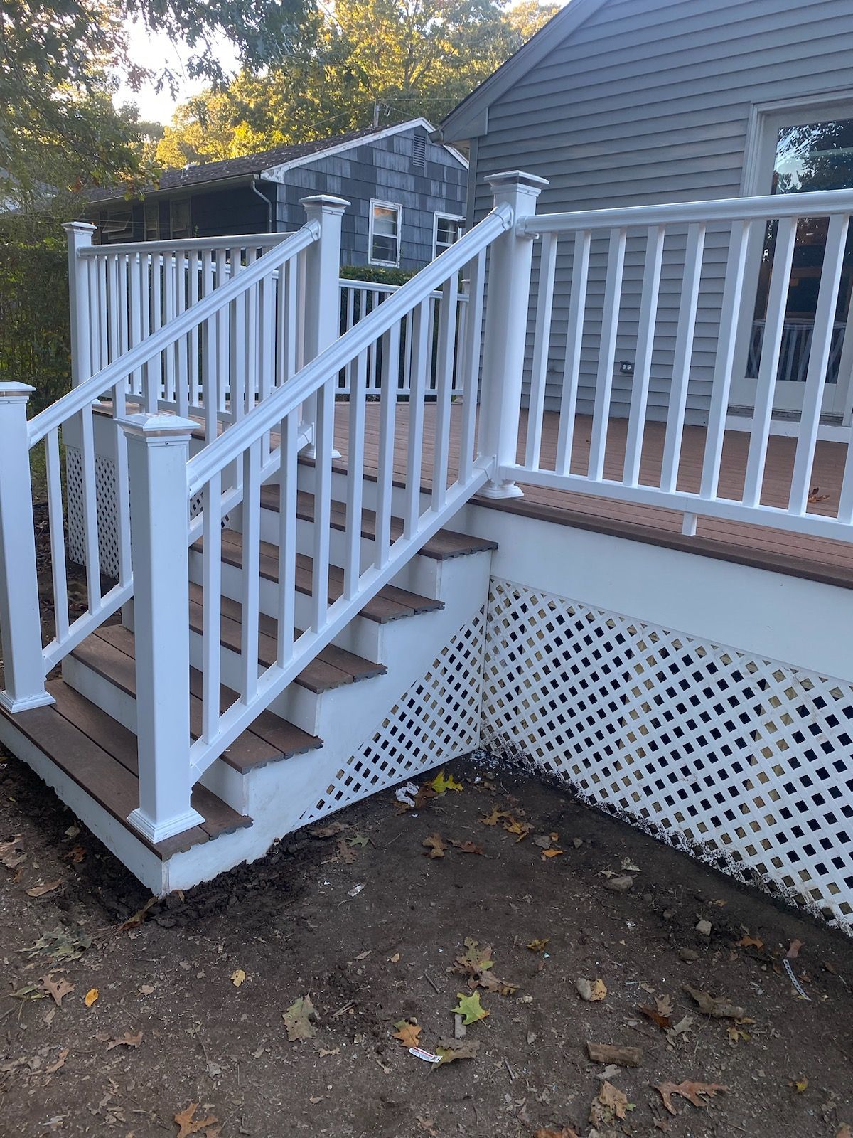 White deck with stairs, railings, and lattice skirting; brown deck boards.