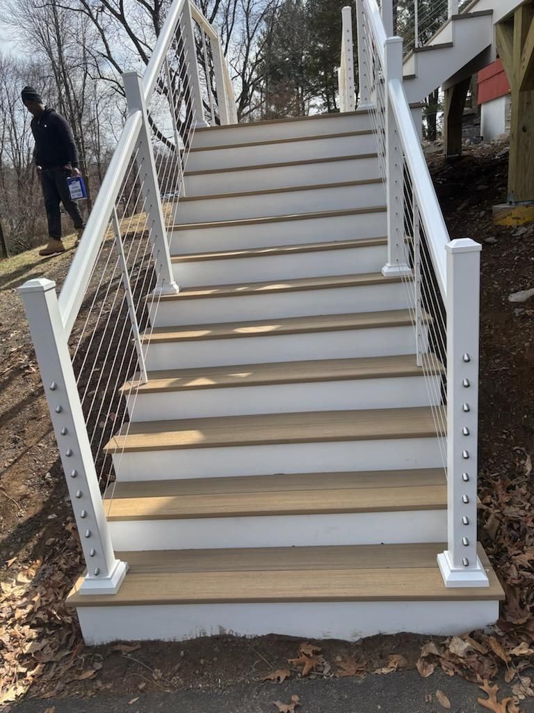 Outdoor staircase with white railing, wood steps, and person standing to the left.