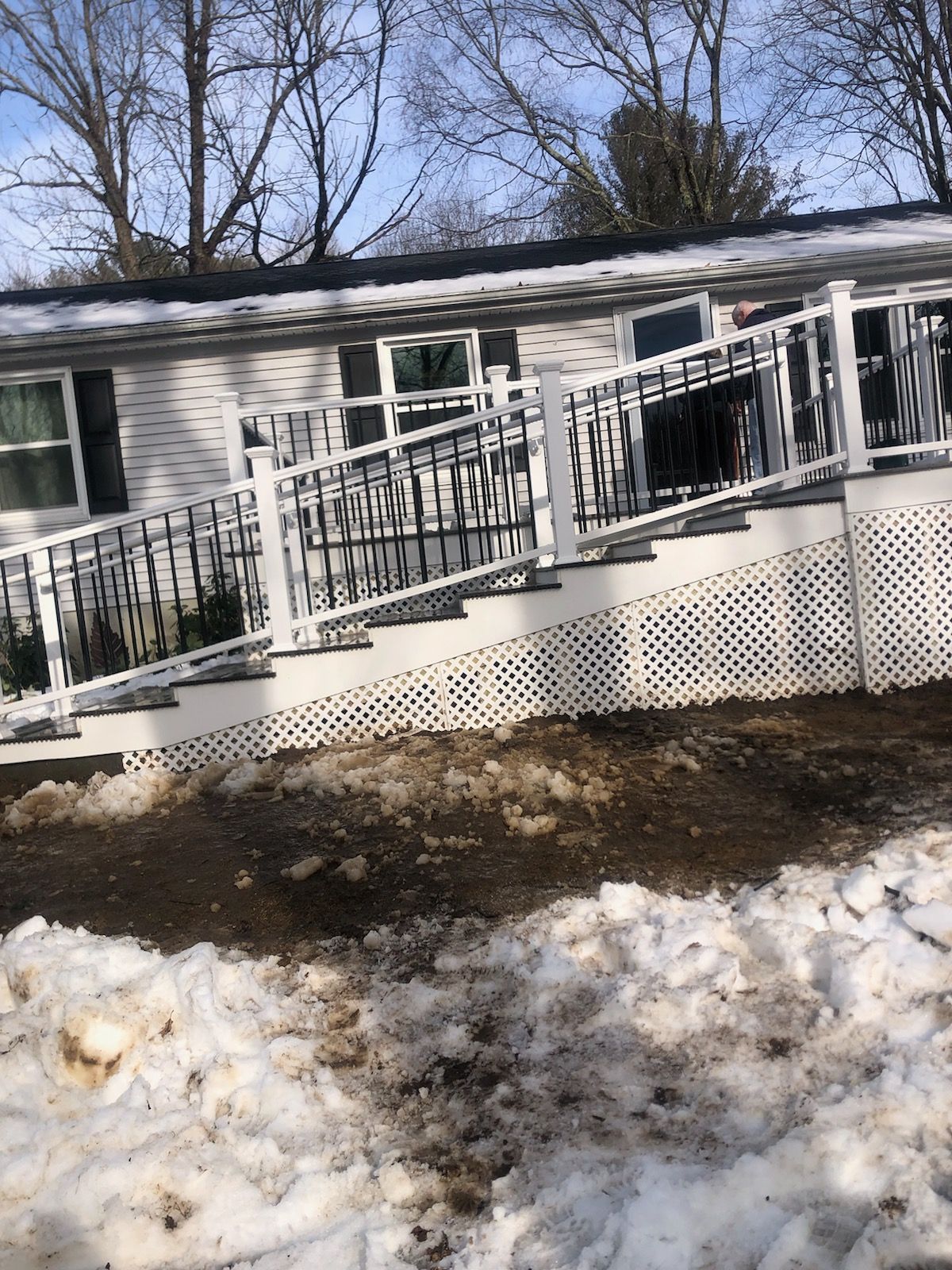White house with a ramp and steps, snow on the ground.