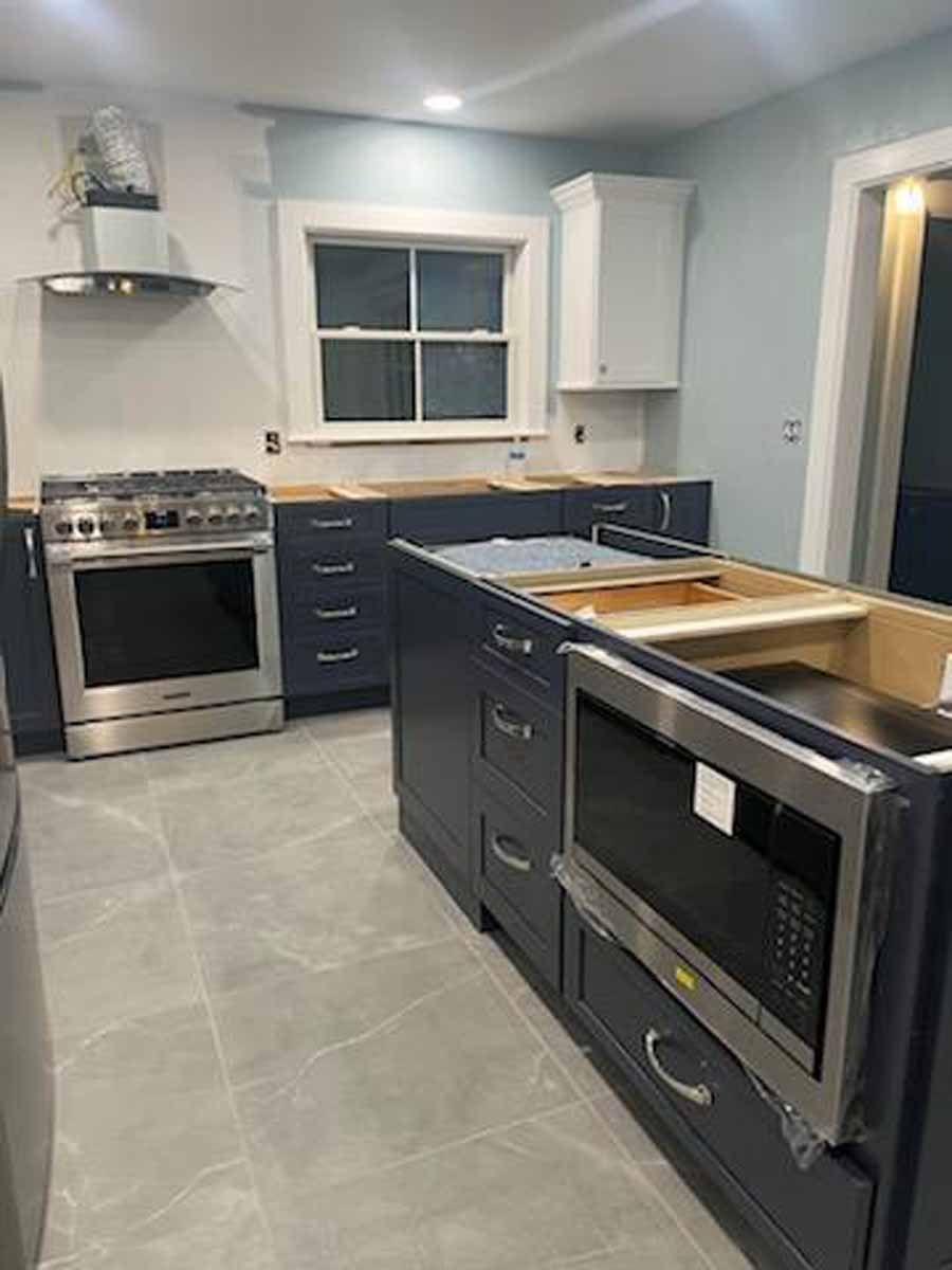Newly renovated kitchen with dark blue cabinets, stainless steel appliances, and a light blue wall.