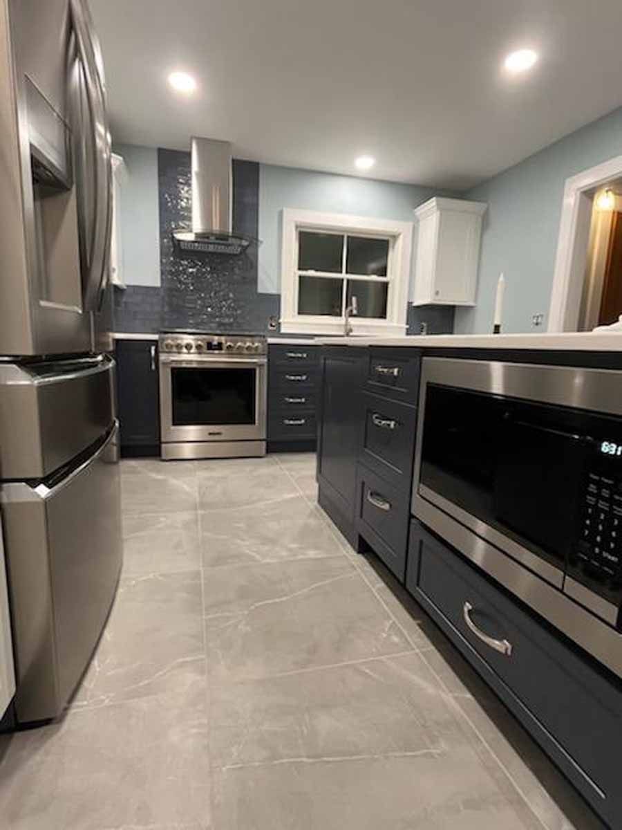 Modern kitchen with gray cabinets, stainless steel appliances, and blue walls.