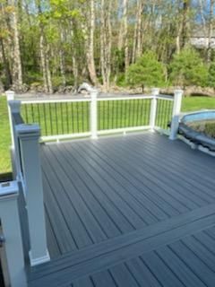 Gray composite deck with white railings and black spindles, overlooking a wooded area.