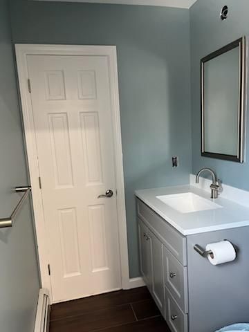 Bathroom with blue walls, white sink, gray cabinet, white door, and silver mirror.