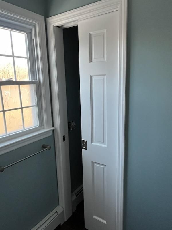 White door partially open in blue-walled room, next to a window with sunlight.