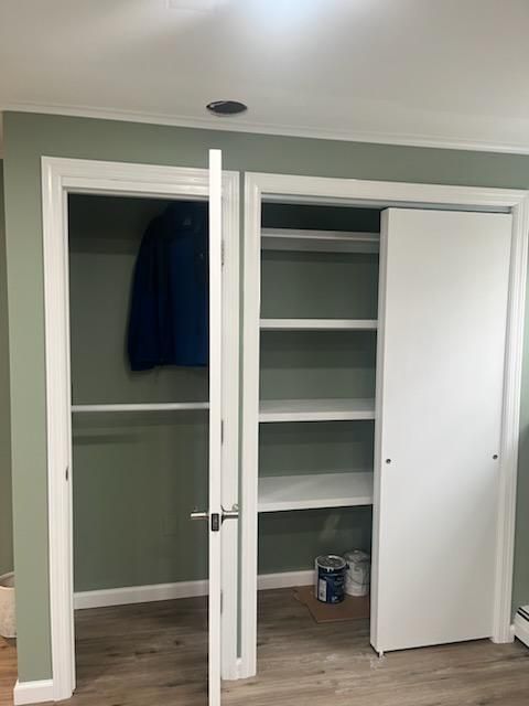 Closet with sliding door. One side has shelves, the other has a clothes rod and a blue jacket. White, green, and light brown colors.