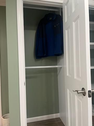 Open white closet door with a blue jacket hanging on a rod.