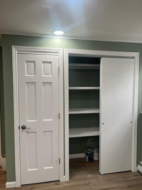 White doors and sliding closet in a room with green walls. Shelves inside the closet.