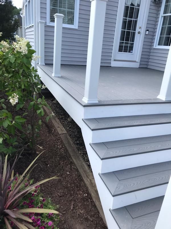 Gray composite deck with white trim and steps, overlooking a garden.