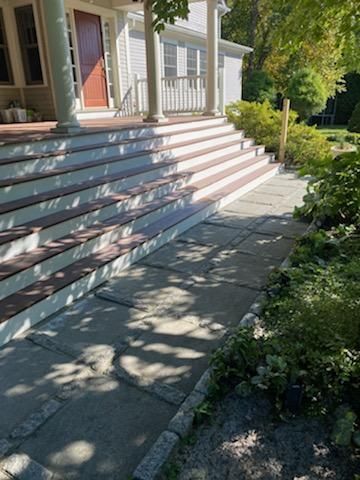 Stone walkway leading to house with multi-level porch steps. Steps are brown/white.