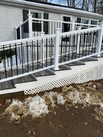Exterior view of a house with a white ramp and railing with black accents. Snow is on the ground.