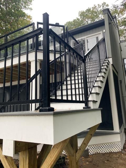 Black and white deck with stairs. Wooden structure. Black railing. White trim.