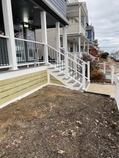 Exterior of a house with a porch and steps, a small lawn, and other houses.