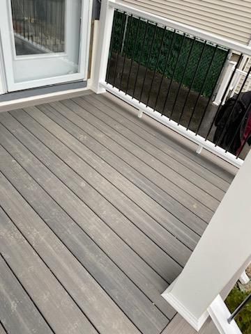 Gray composite deck with white railing and glass door.
