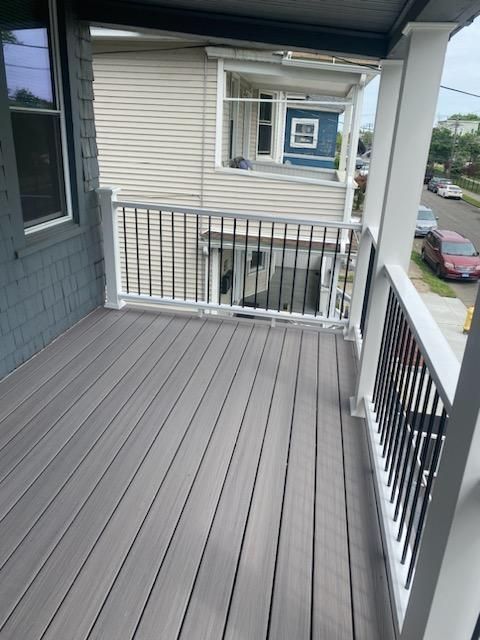 Gray composite deck with white railing, black balusters, and gray siding.