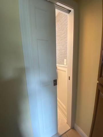 White sliding door partially open, revealing a bathroom with a white wall and a light-colored floor.