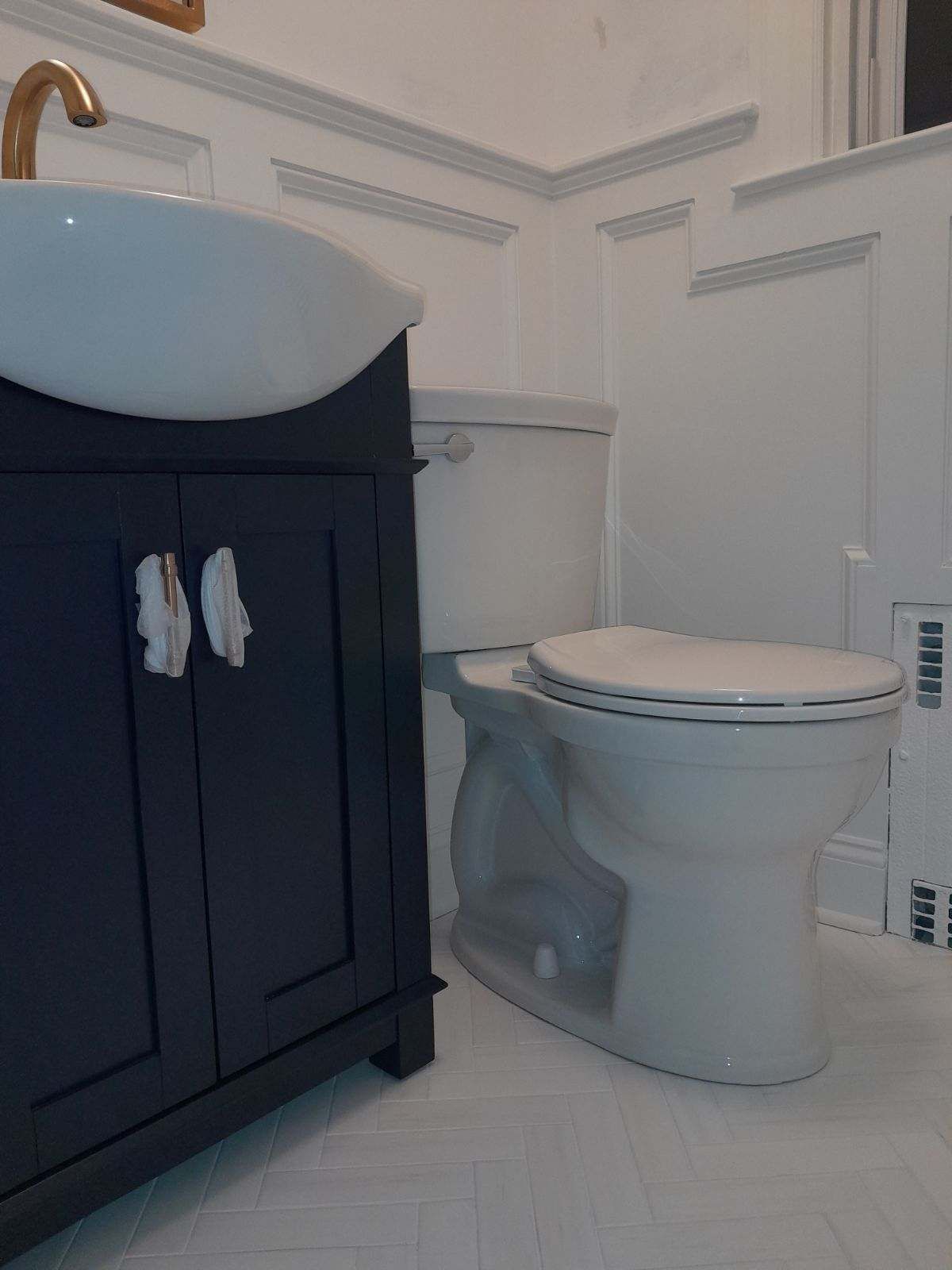 Dark blue vanity with white sink, next to white toilet in bathroom.