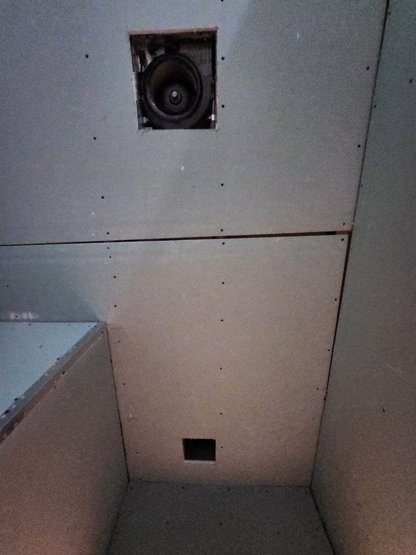 Drywall ceiling with a recessed speaker and a small square vent.