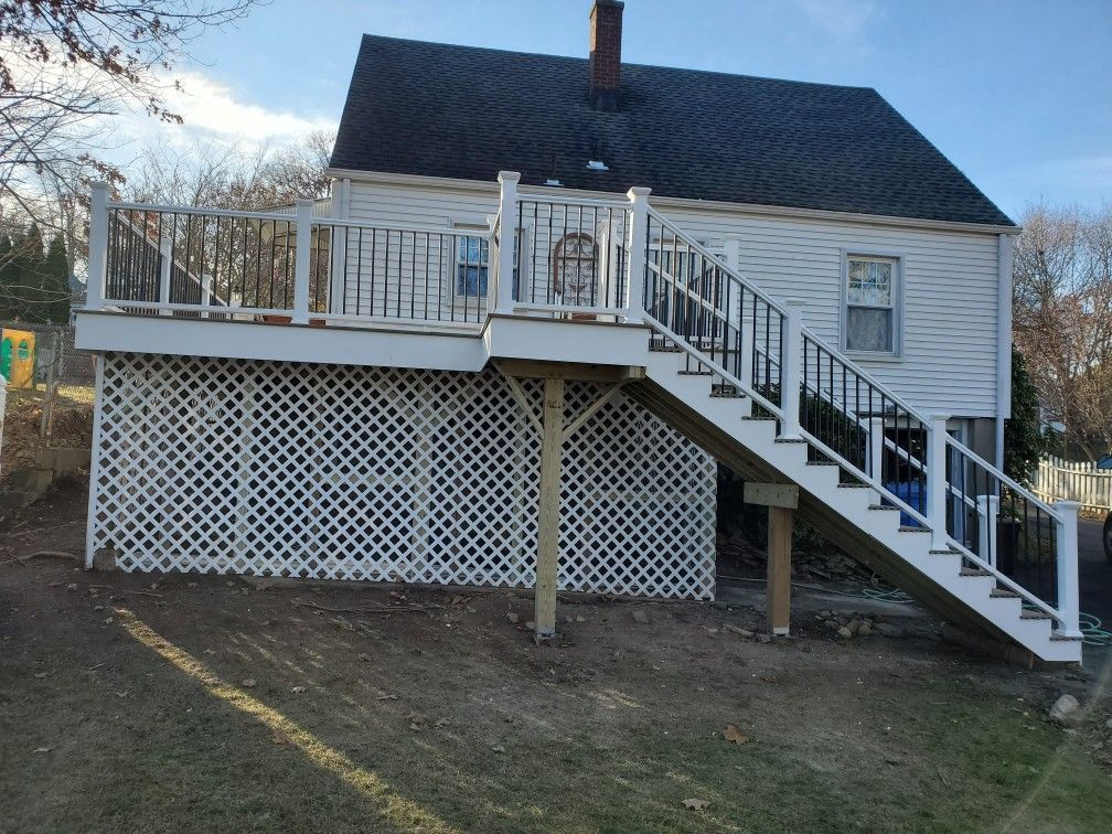 White house with a large deck and staircase. Lattice under deck. Brown supports.