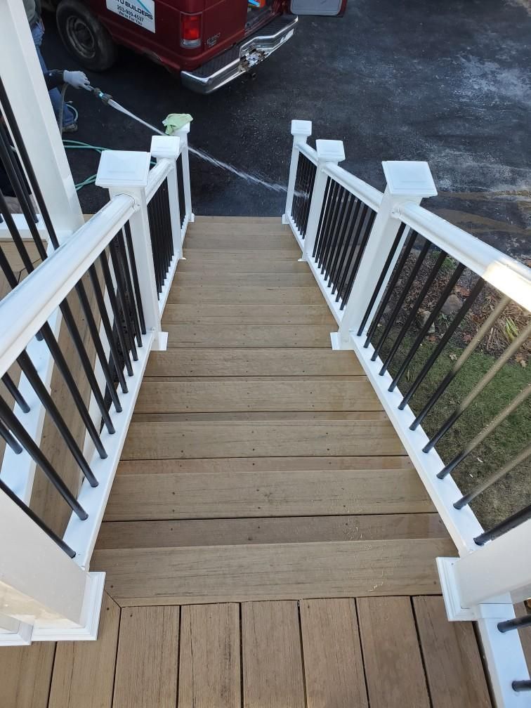 Wooden outdoor staircase with black railings and white posts, leading downwards.