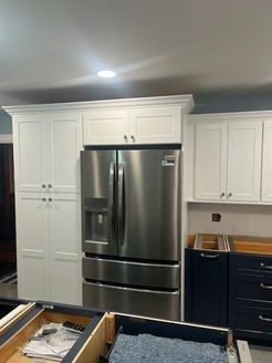 Stainless steel refrigerator with white cabinetry in kitchen.