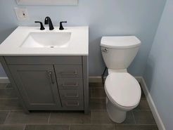 Bathroom with gray vanity and sink, a white toilet, and blue walls.