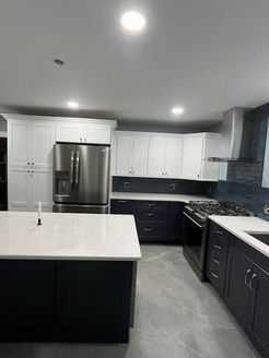 Modern kitchen with white and navy blue cabinets, stainless steel appliances, and a central island.