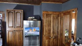 Kitchen corner with wood cabinets and trim, stainless steel refrigerator, and dark blue walls.