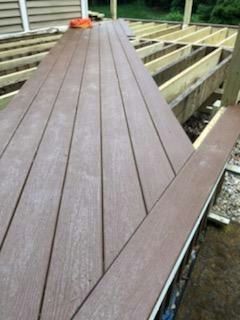Deck under construction; brown composite decking boards laid over the wooden frame.