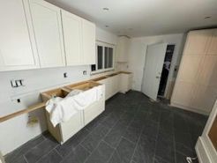 Kitchen under renovation with white cabinets, dark tiled floor, and unfinished countertops.