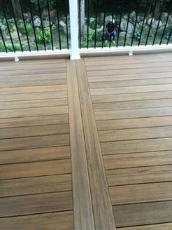 Composite wood deck with vertical center boards, railing, and person in the background.