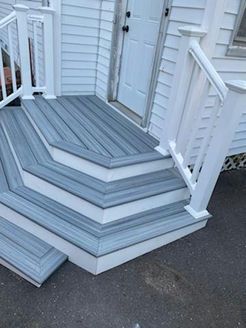 Gray and white deck with three steps leading to a white door.