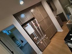 Kitchen with gray cabinets, stainless steel refrigerator, and wood floor.