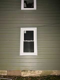 Green siding with two white-framed windows, one above the other.