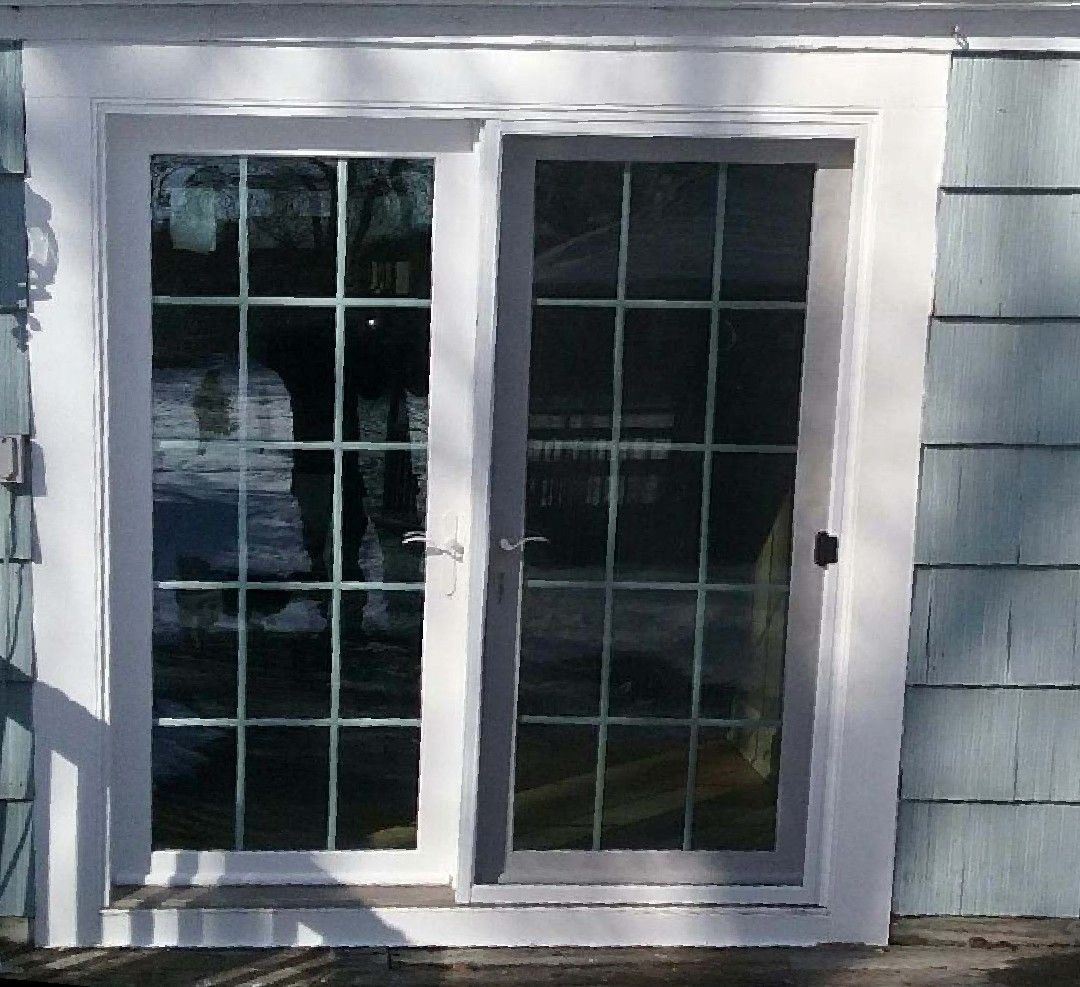 Sliding glass door with white frame and grids, set in blue siding wall.