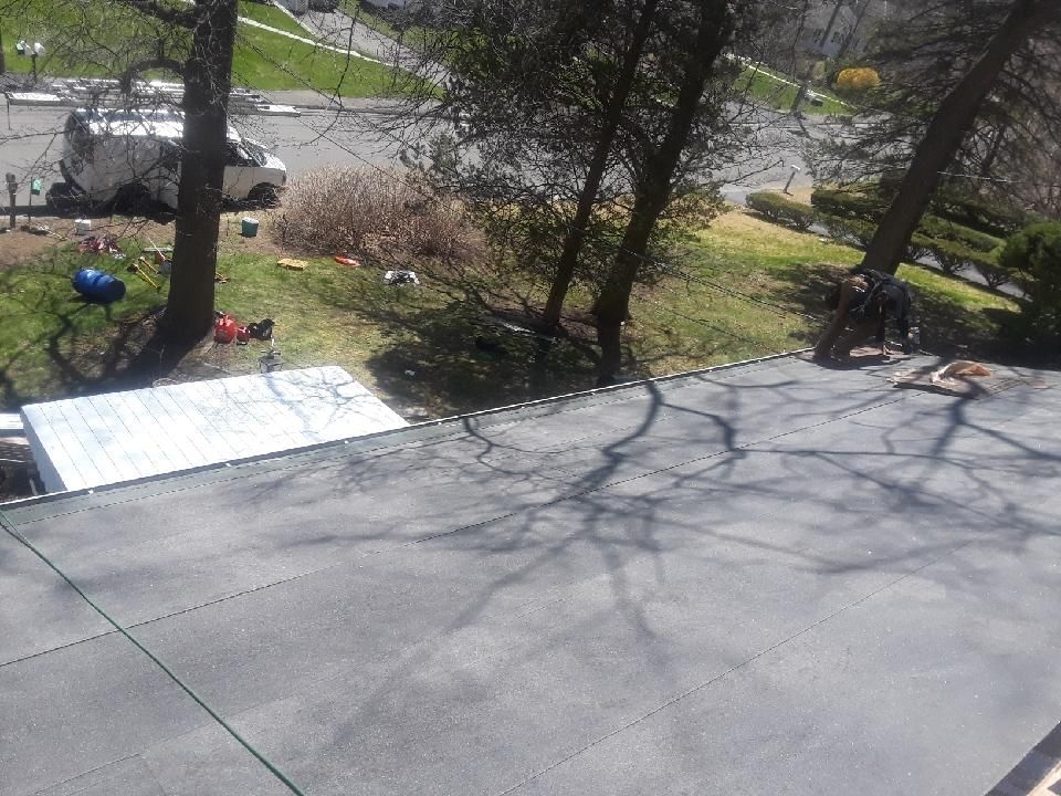 View from rooftop of asphalt with trees casting shadows, grassy area with a van.