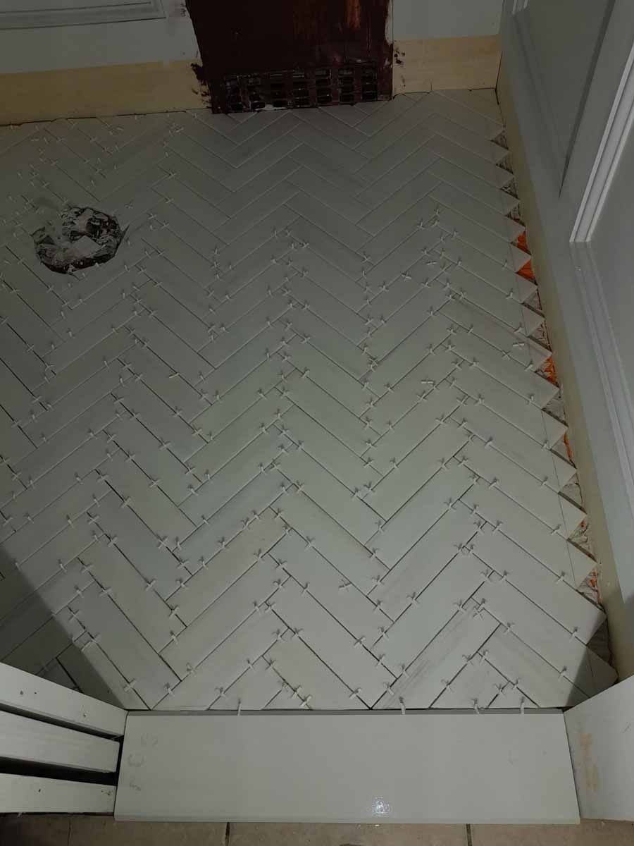 Herringbone tile floor in a room with white trim.
