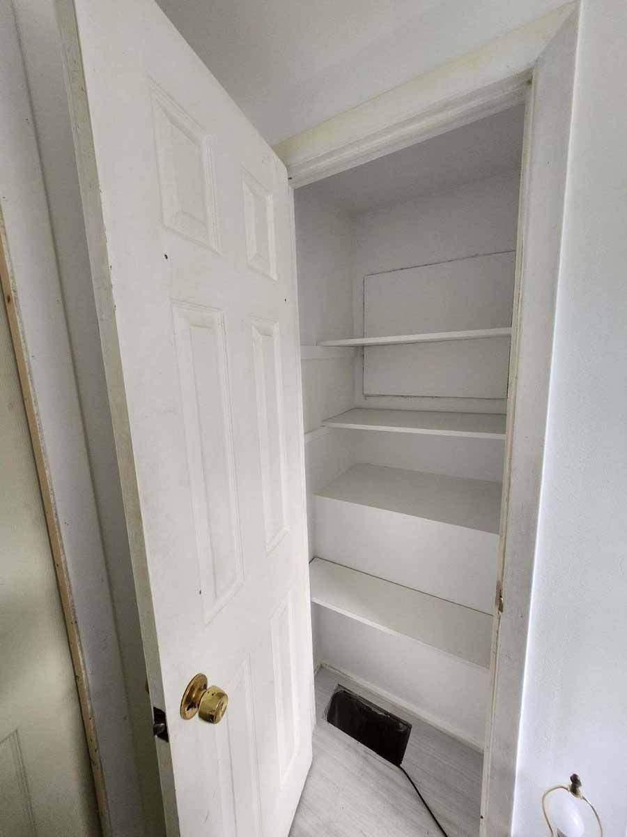 White closet with shelves and a partially open door. The interior is painted white.