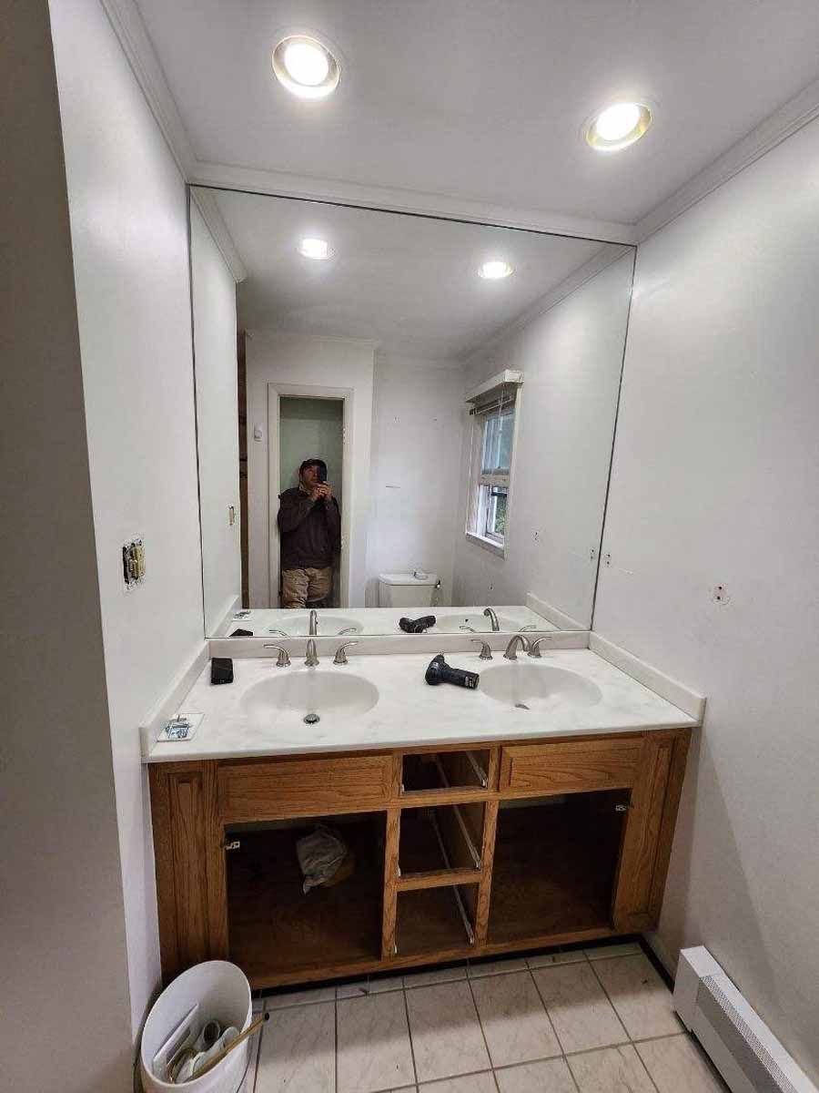 Bathroom with double sinks, large mirror, and open cabinets. Person reflected in mirror.