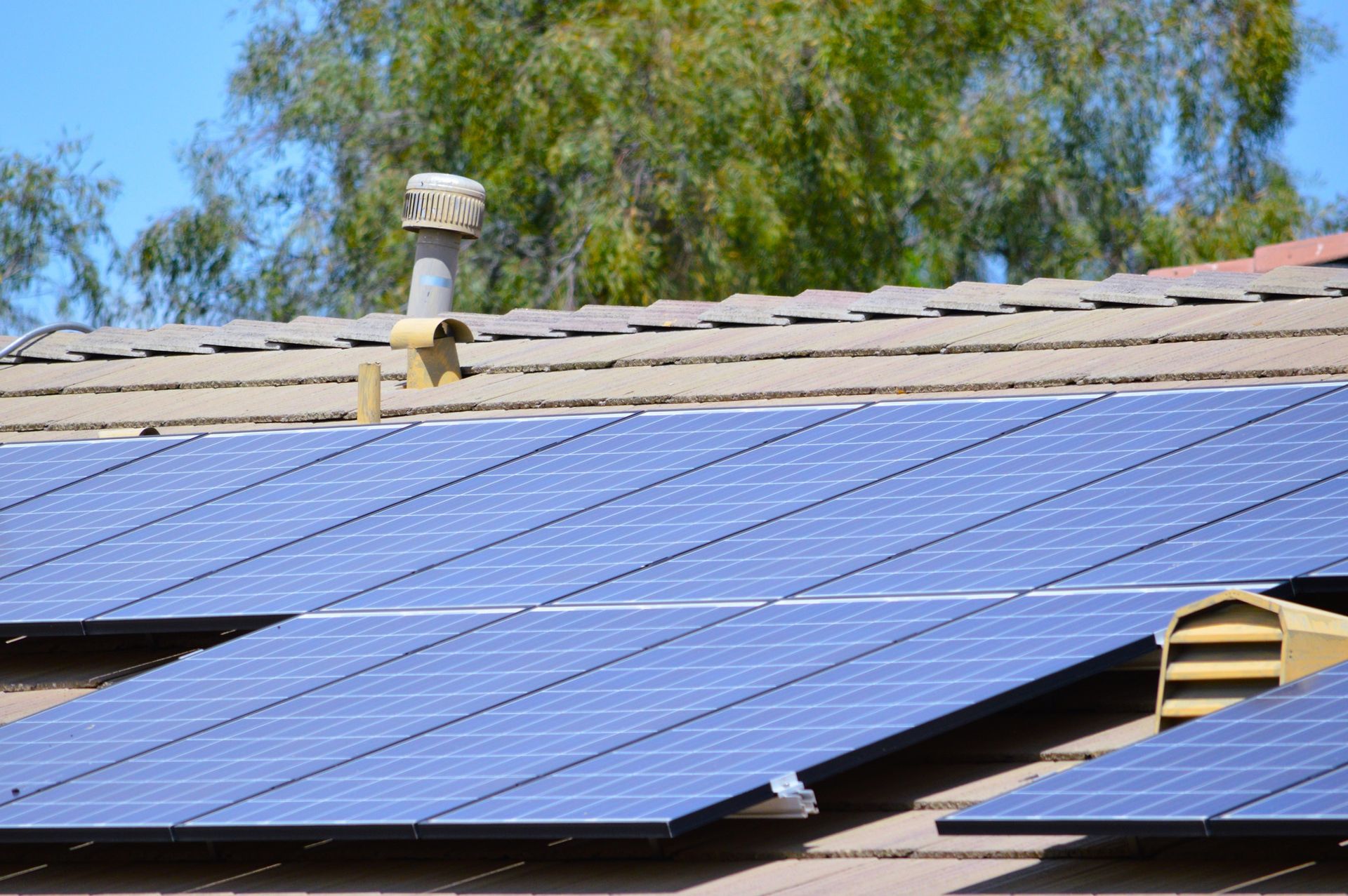Solar panels on a brown tiled roof, capturing sunlight. A vent pipe is also visible.