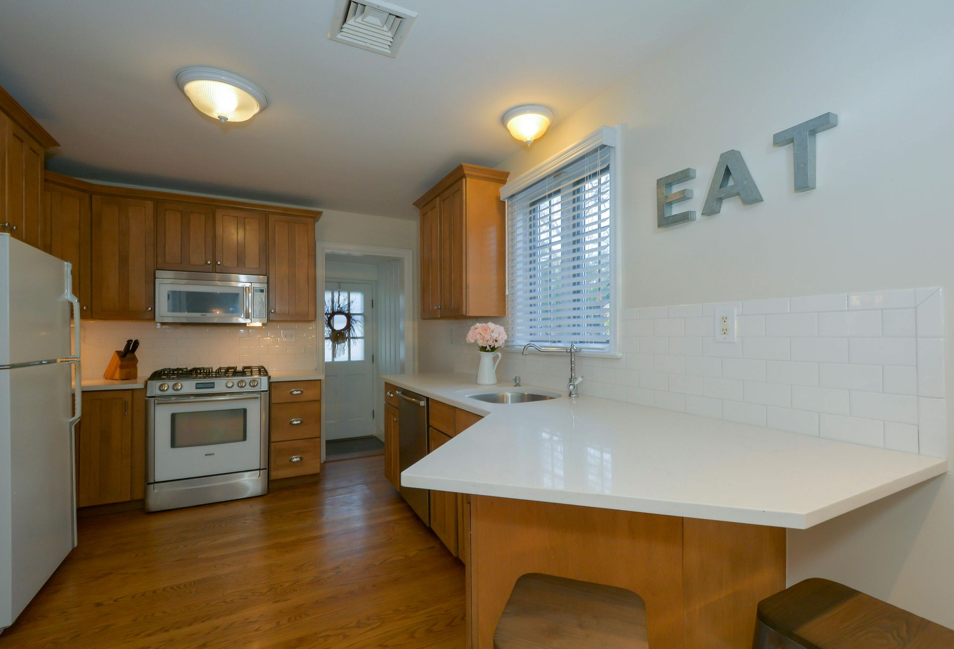 A kitchen with white cabinets , stainless steel appliances , a refrigerator and a stove