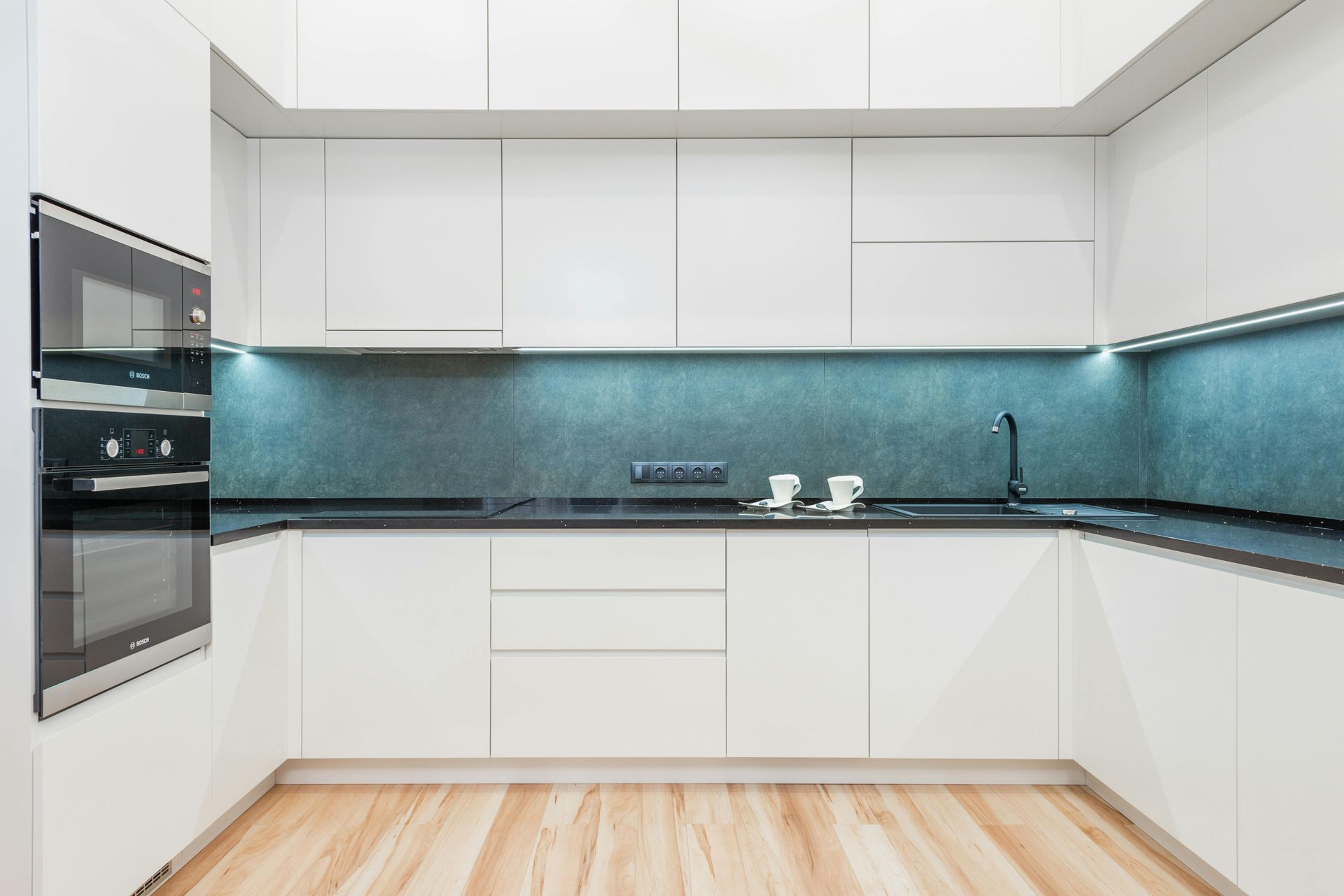 A kitchen with white cabinets , stainless steel appliances , a sink , and a window.