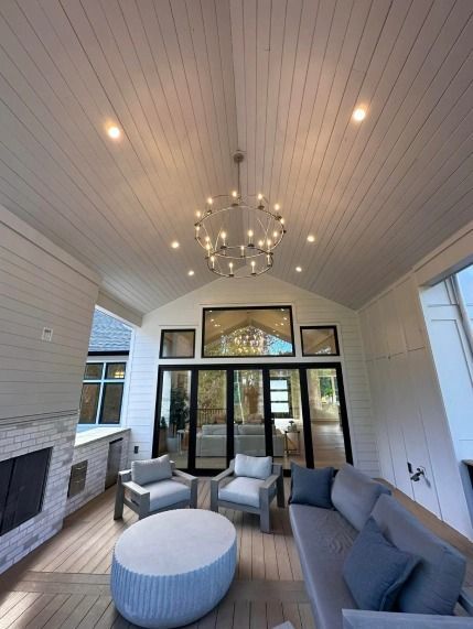 A living room with a couch and chairs and a chandelier hanging from the ceiling