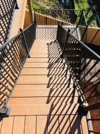 A wooden deck with stairs and a metal railing.