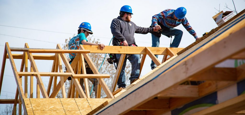A group of construction workers are working on the roof of a building in Queens, NY.