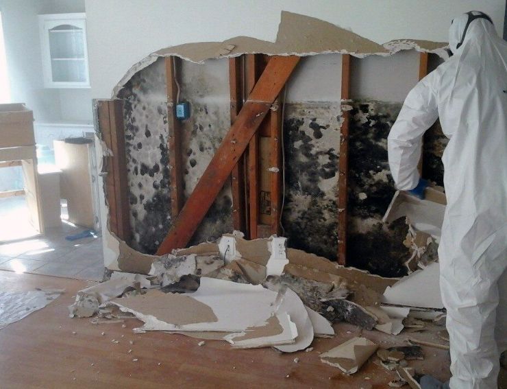 A man in a protective suit is working on a wall