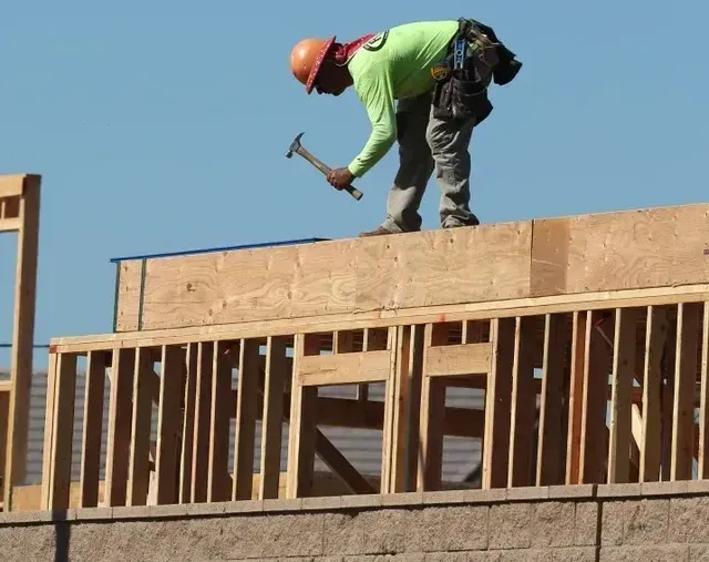 A construction worker is working on the roof of a building in Queens, NY.