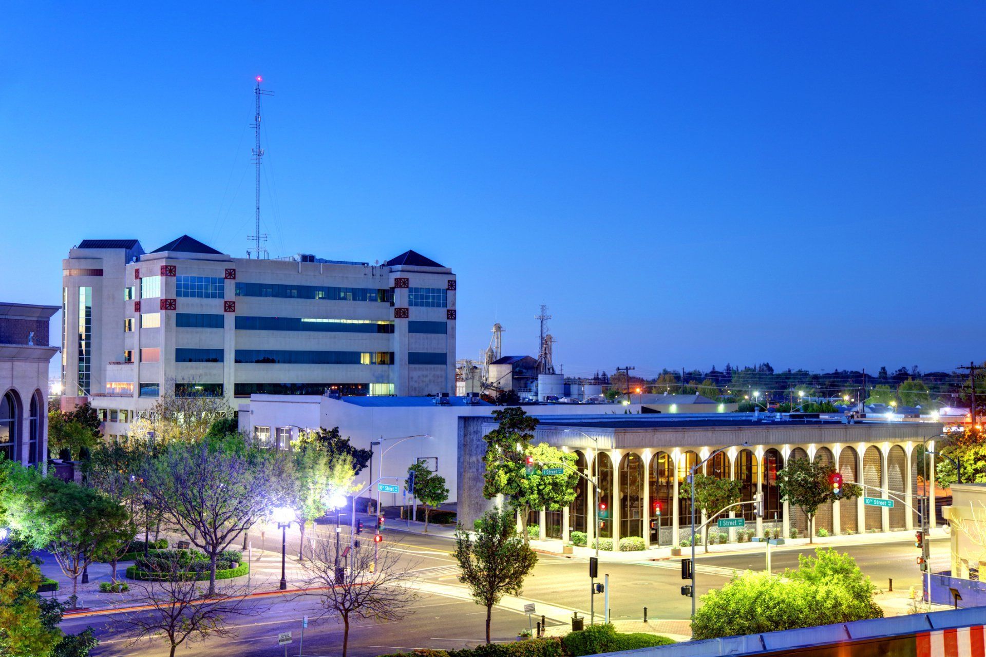 City buildings at dusk, streetlights illuminate a downtown area.