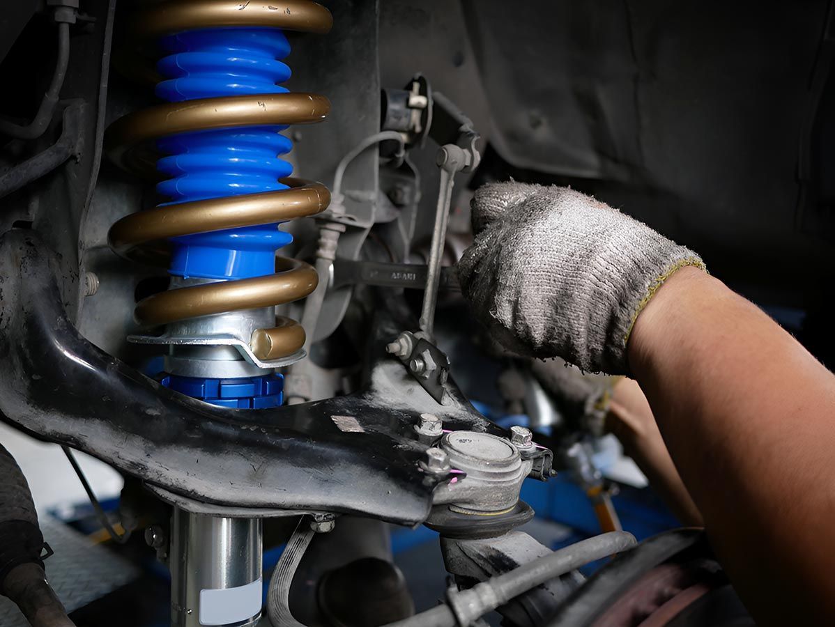 A Person is Working on a Car Suspension With a Wrench — Cairns Mechanical Workshop In Bungalow, QLD